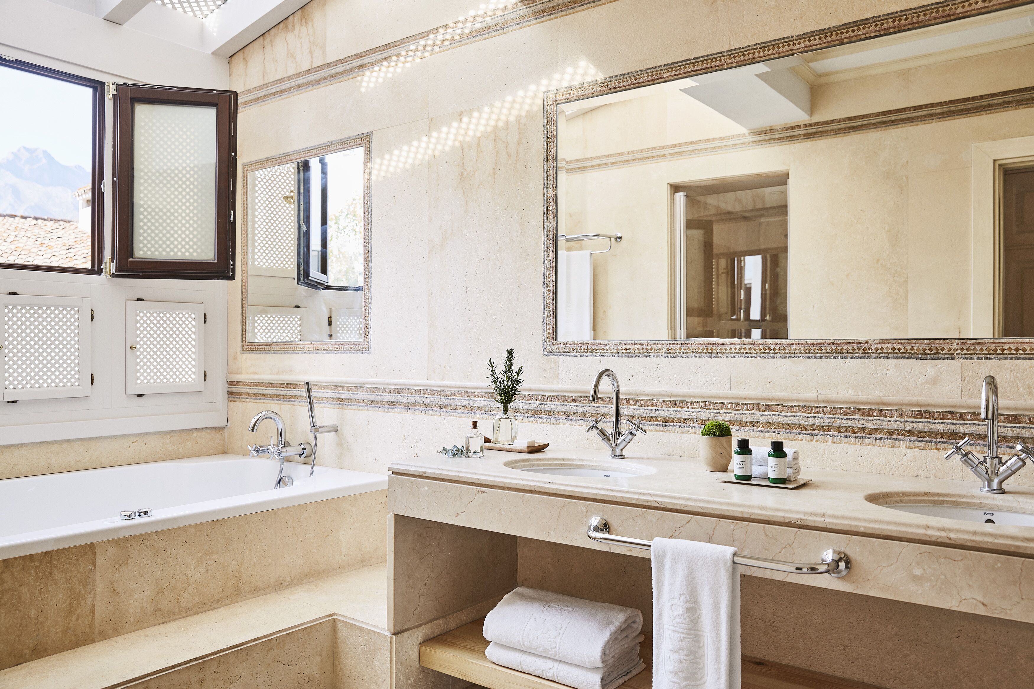 A modern bathroom with two sinks, a large mirror, and a window.