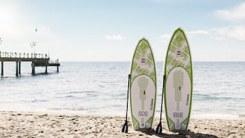 Two surfboards on a sandy beach with a pier in the background.