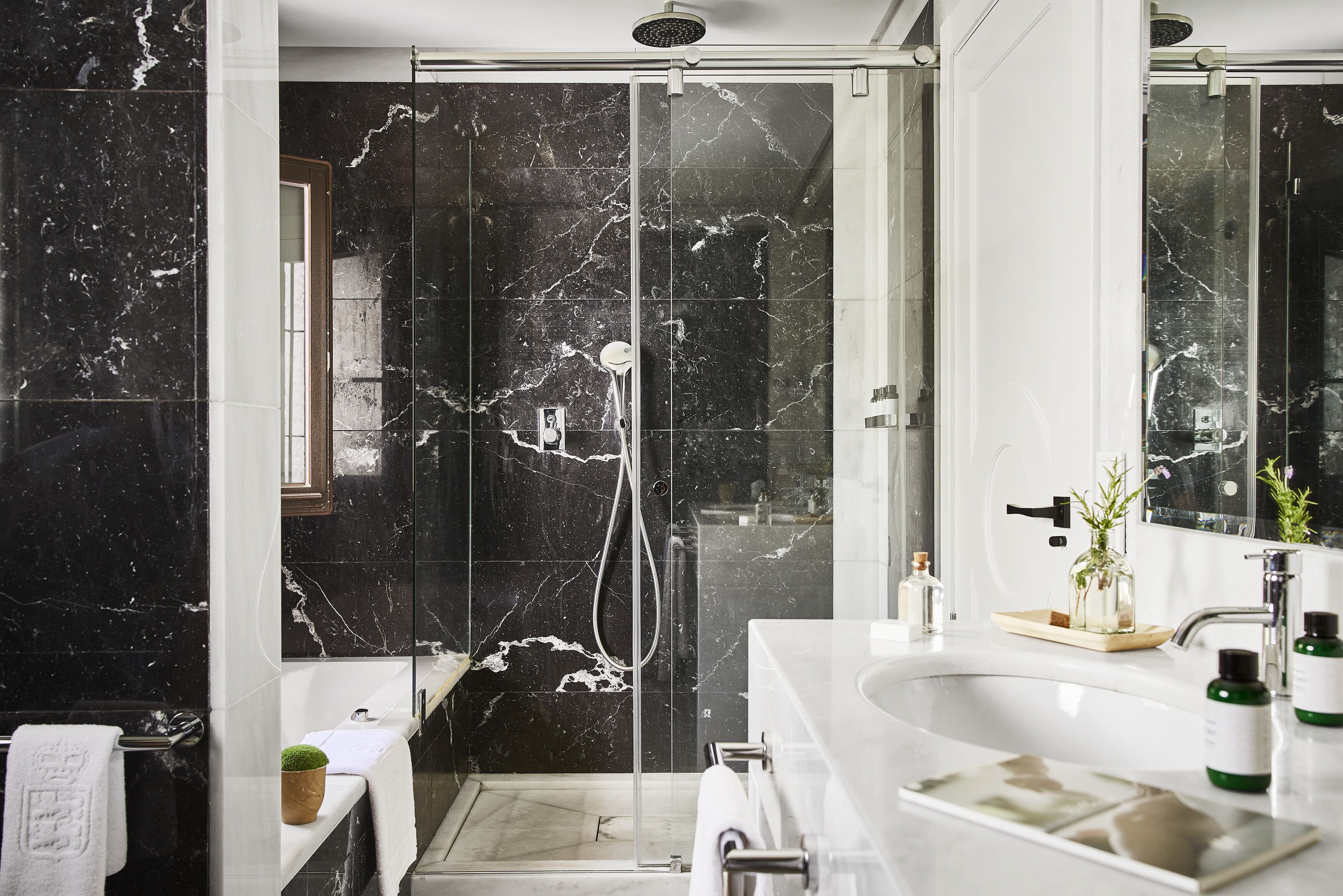 A modern bathroom with a glass-enclosed shower, a white sink, and a marble backsplash.