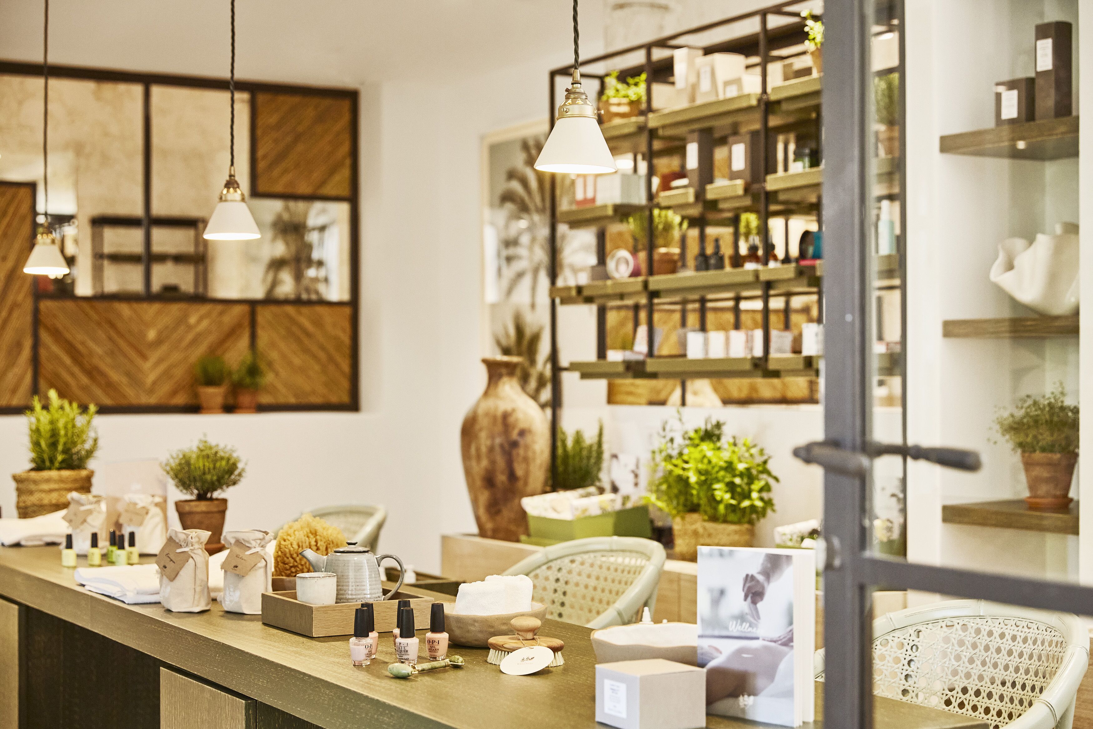 Een verzorgd ontvangstgedeelte van een spa met een houten balie, diverse spa-producten en een grote spiegel.