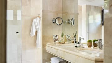 A modern bathroom with a glass shower enclosure, a marble sink, and a large mirror.