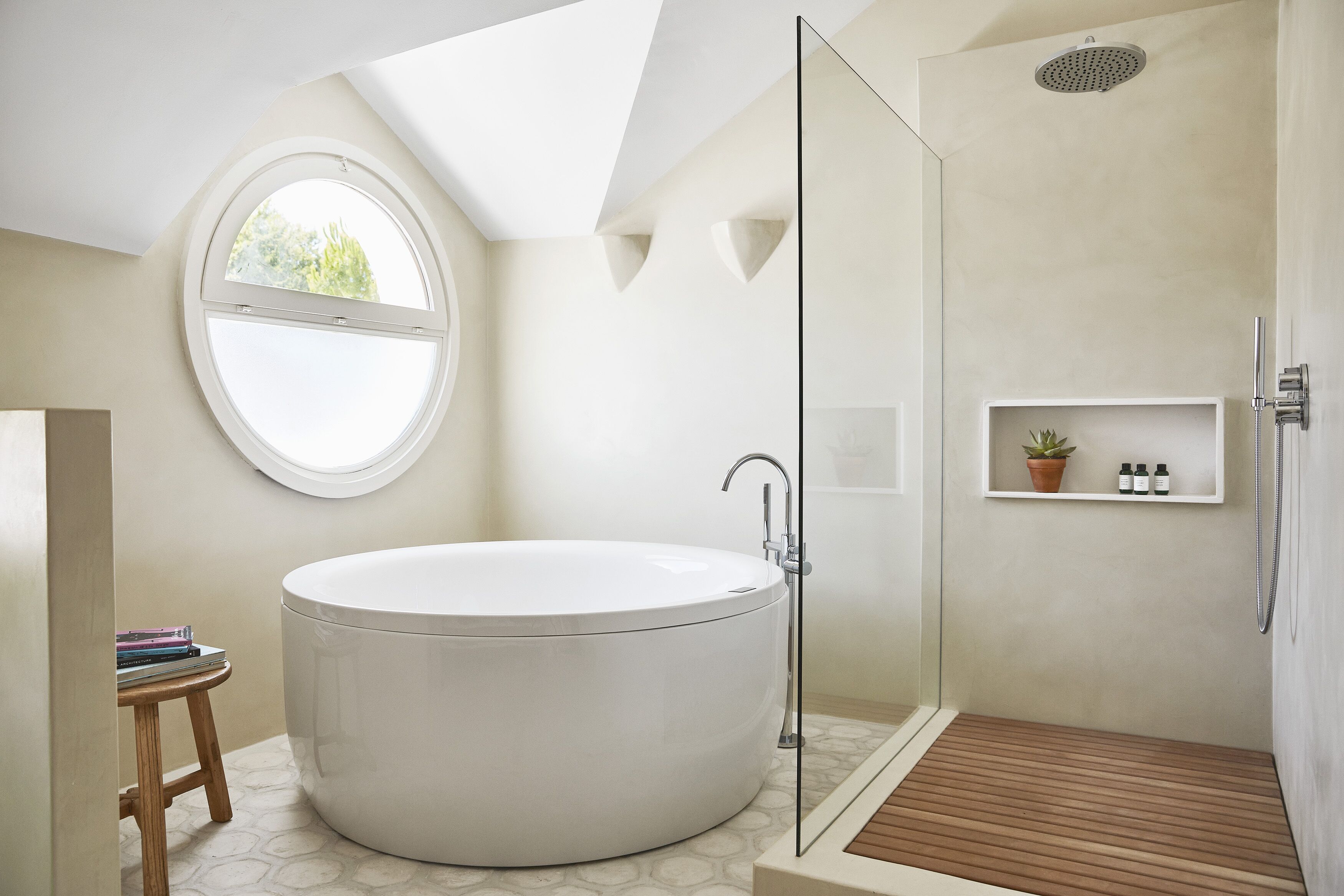 A modern bathroom with a freestanding bathtub, a glass-enclosed shower, and a small wooden stool.
