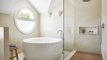 A modern bathroom with a freestanding bathtub, a glass-enclosed shower, and a small wooden stool.