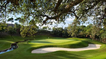 Un campo de golf bien cuidado con un obstáculo acuático, búnkeres de arena y un marcador de posición.
