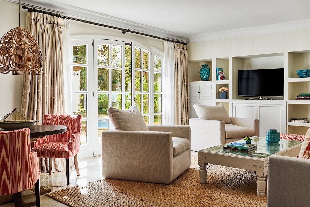 A living room with a sofa, armchairs, a coffee table, and a television.