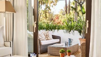 An open doorway to a patio area with wicker furniture, a table, and potted plants.