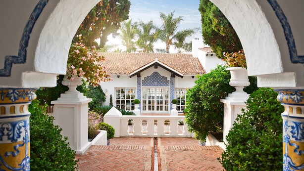 A courtyard with a tiled floor, a white building with a tiled roof, and a blue and white tiled archway. - Marbella Club Hotel Golf Resort & Spa (Marbella)