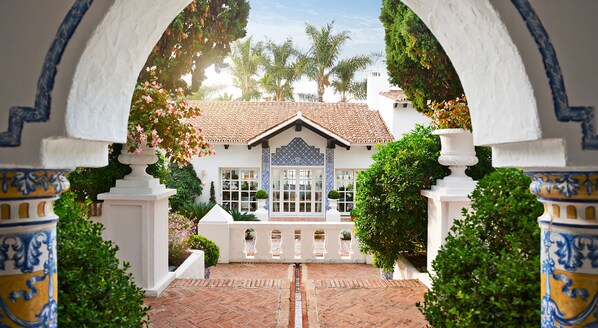 Traditional Mediterranean villa with a central courtyard surrounded by lush greenery and decorative tiles.