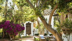 A courtyard with a pool, a wooden table, and chairs, surrounded by lush greenery and a traditional door. - Marbella Club Hotel Golf Resort & Spa (Marbella)
