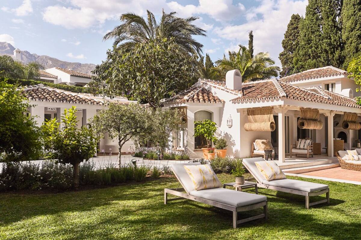 A villa with a swimming pool, outdoor seating, and lush greenery.