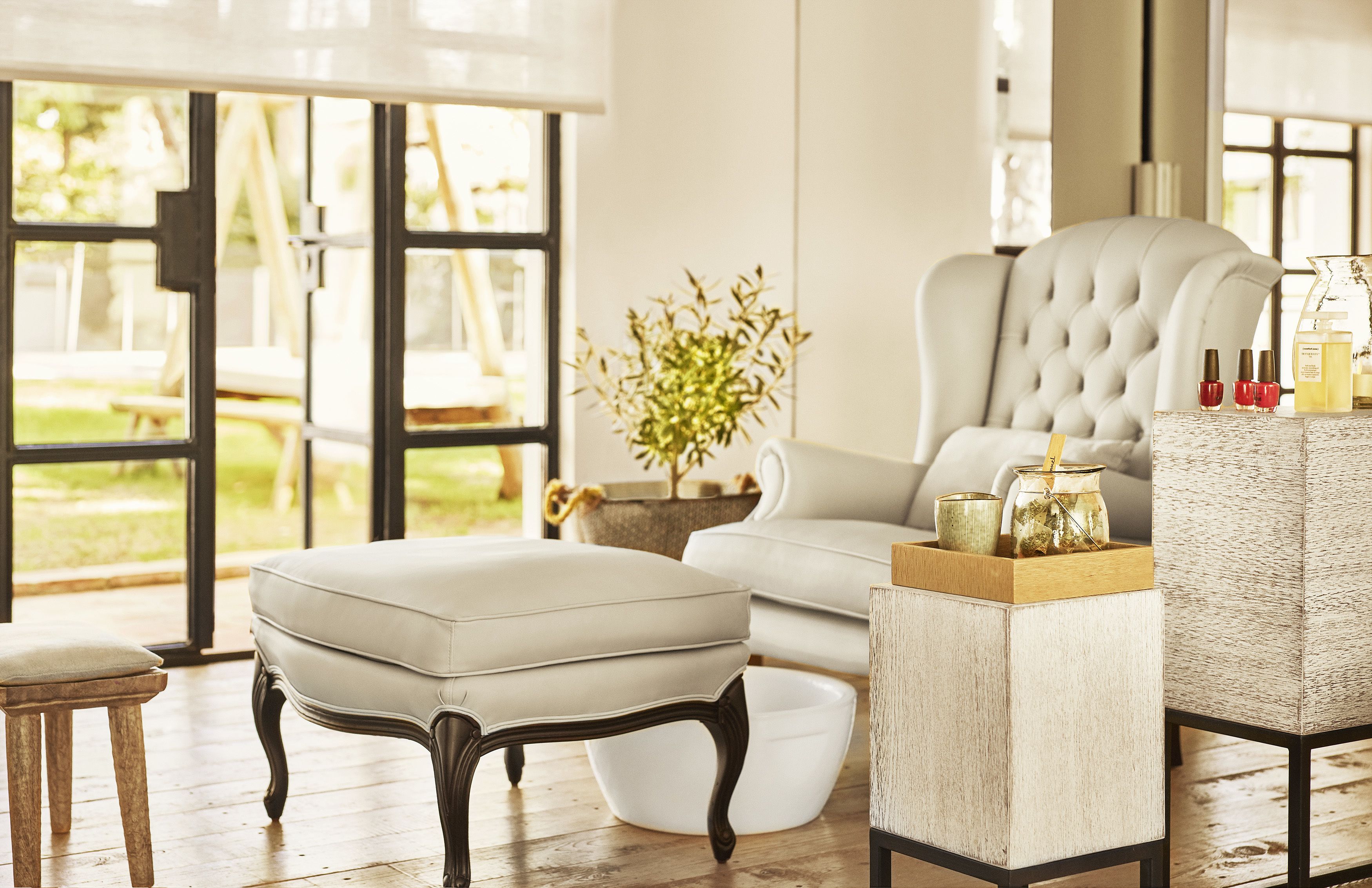 A modern living room with a white sofa, a tufted armchair, a wooden coffee table, and a potted plant.