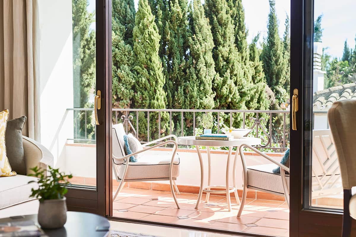 A balcony with a table, chairs, and a sofa.