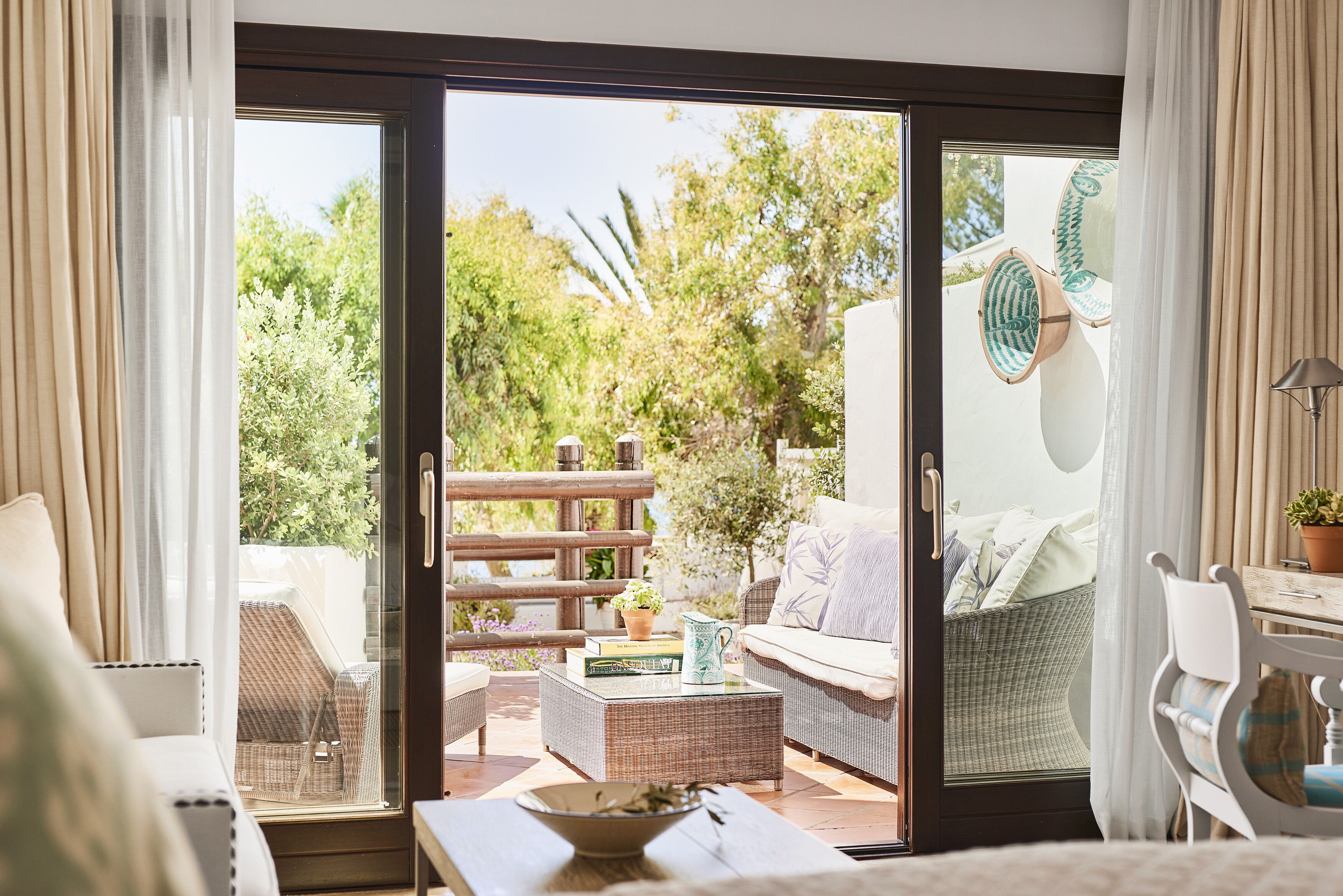 Una habitación acogedora con una puerta corrediza de vidrio que da a un espacio exterior con mobiliario.