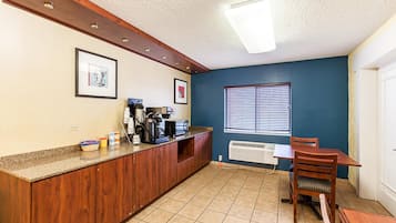 Une cuisine avec un plan de travail en bois, une machine à café et une fenêtre équipée de stores.