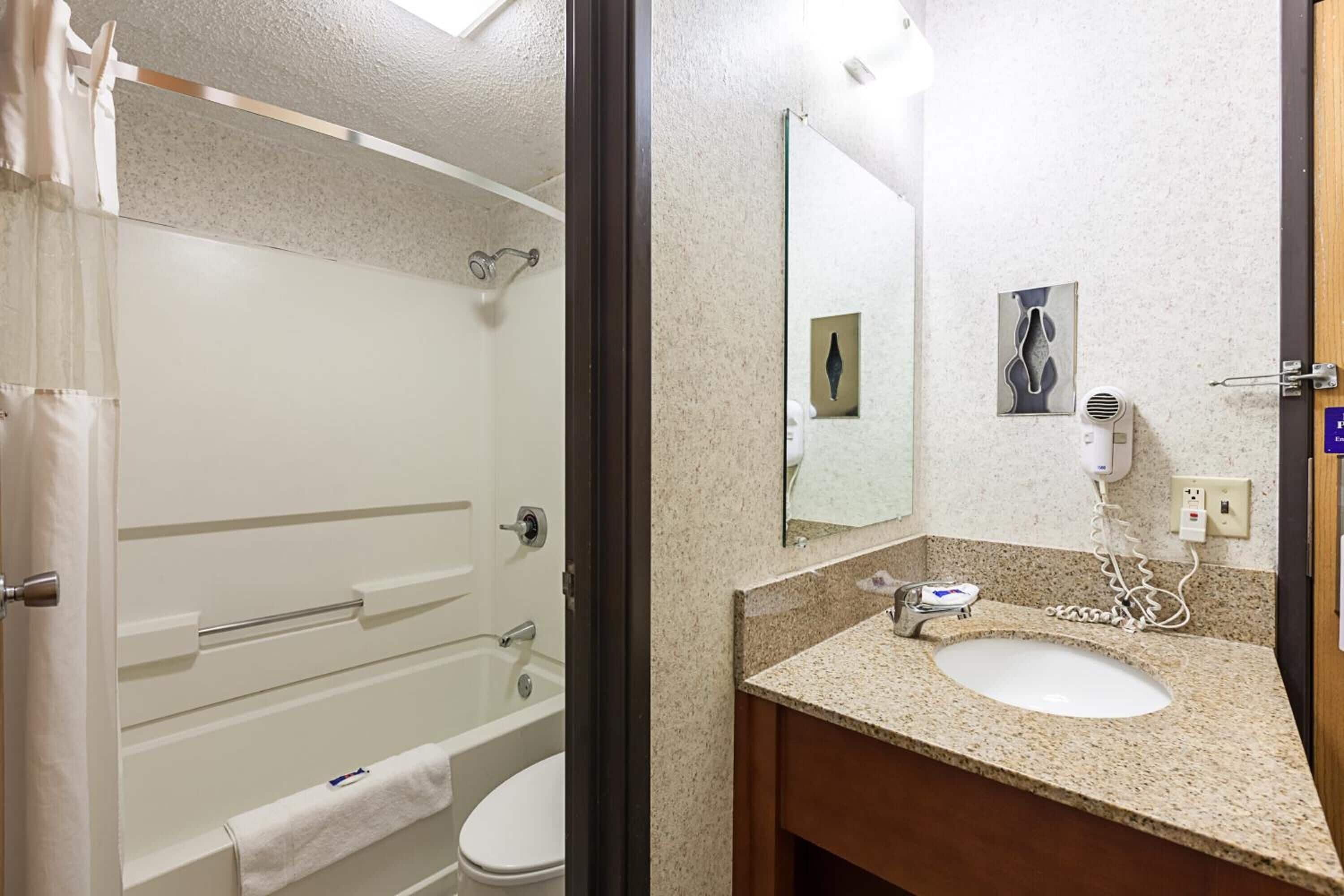 A bathroom with a shower, toilet, sink, and a mirror.