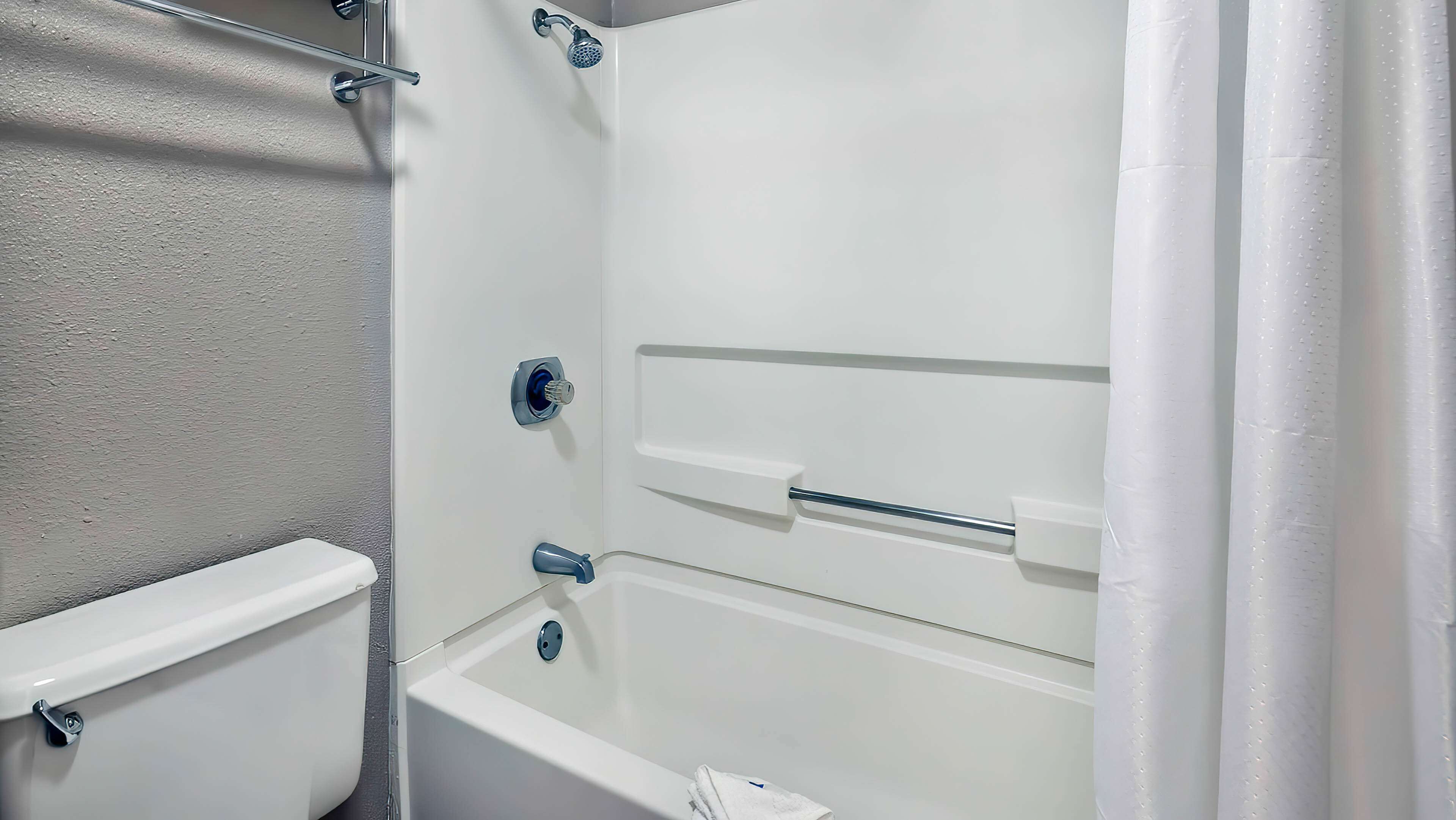 A bathroom with a bathtub, toilet, and shower area.