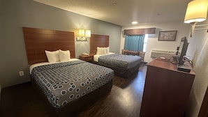 Habitación de hotel con dos camas, un escritorio, una silla y un televisor.