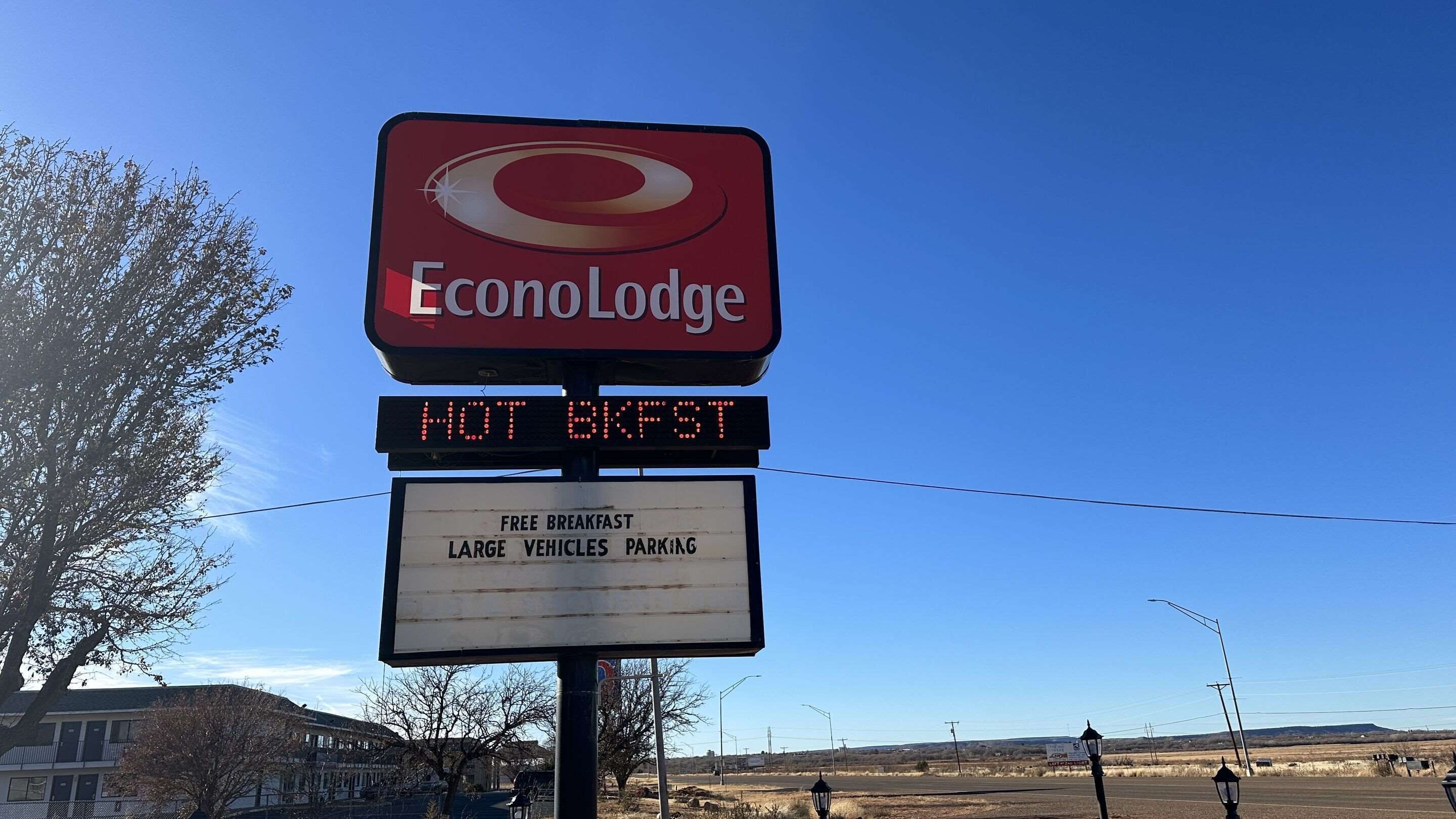 Señal de EconoLodge con servicios que incluyen desayuno gratuito, estacionamiento para vehículos grandes y desayuno caliente.