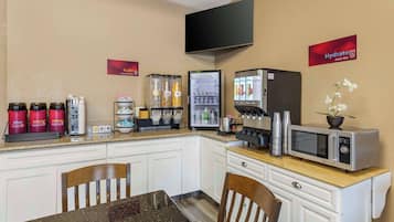 A kitchenette with a microwave, coffee maker, and beverage dispensers.