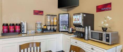 A kitchenette with a microwave, coffee maker, and beverage dispensers.