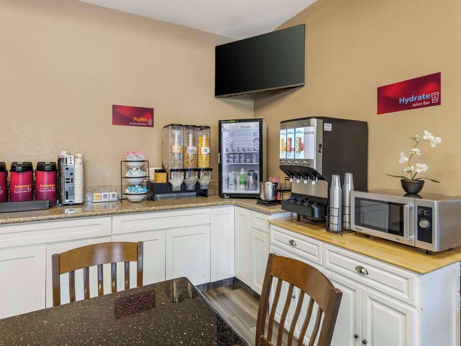 Una kitchenette con microondas, cafetera y dispensadores de bebidas.