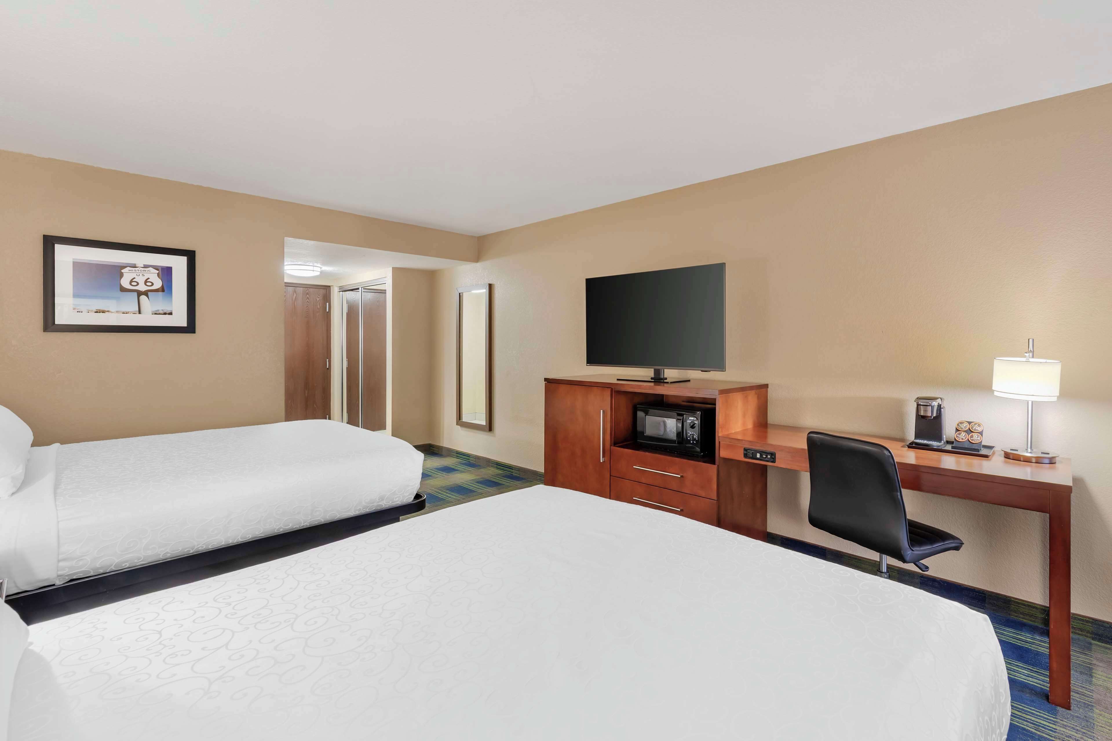 A hotel room with two beds, a desk with a TV, a microwave, and a coffee maker.