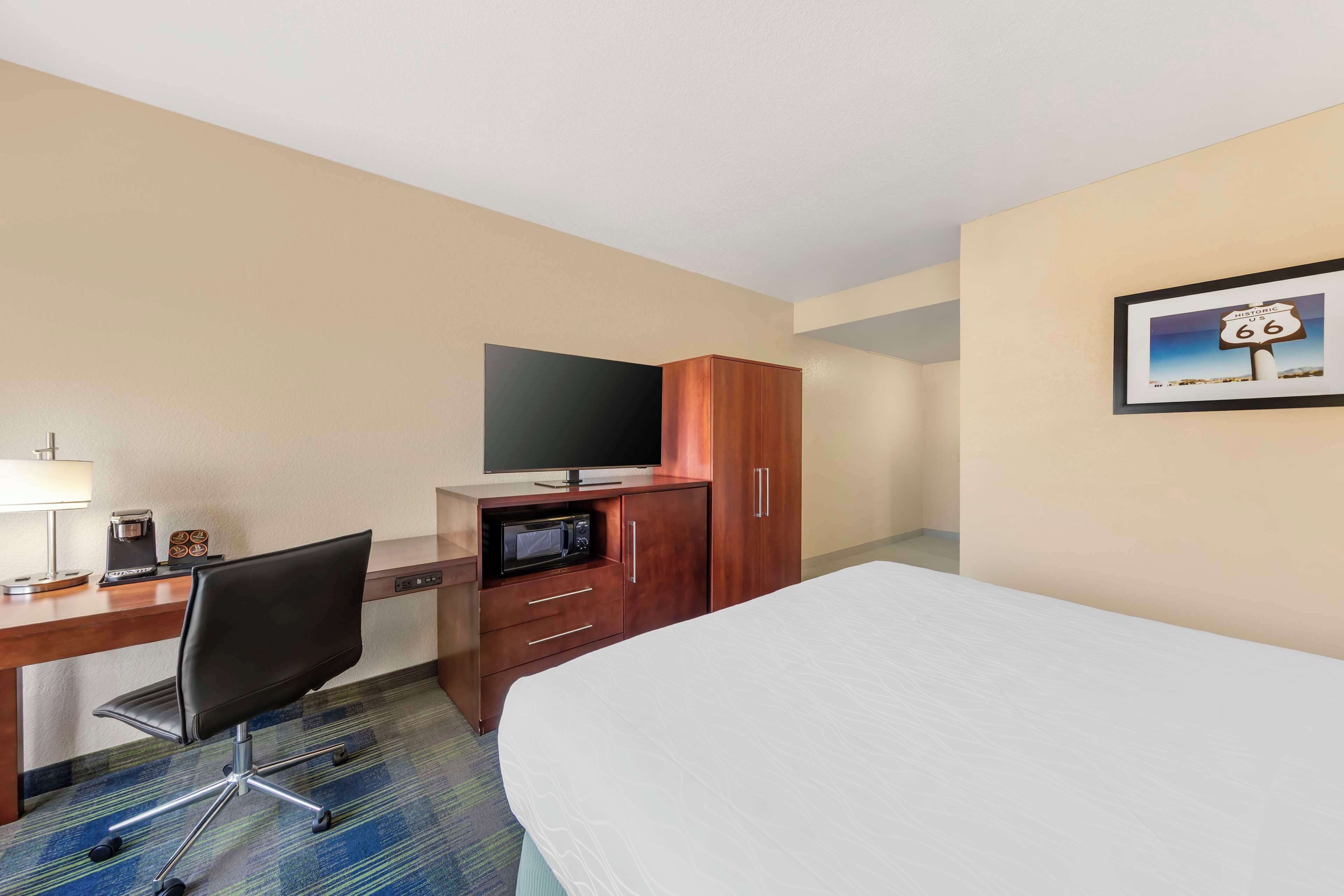 A hotel room with a bed, a desk with a television, a microwave, and a coffee maker.