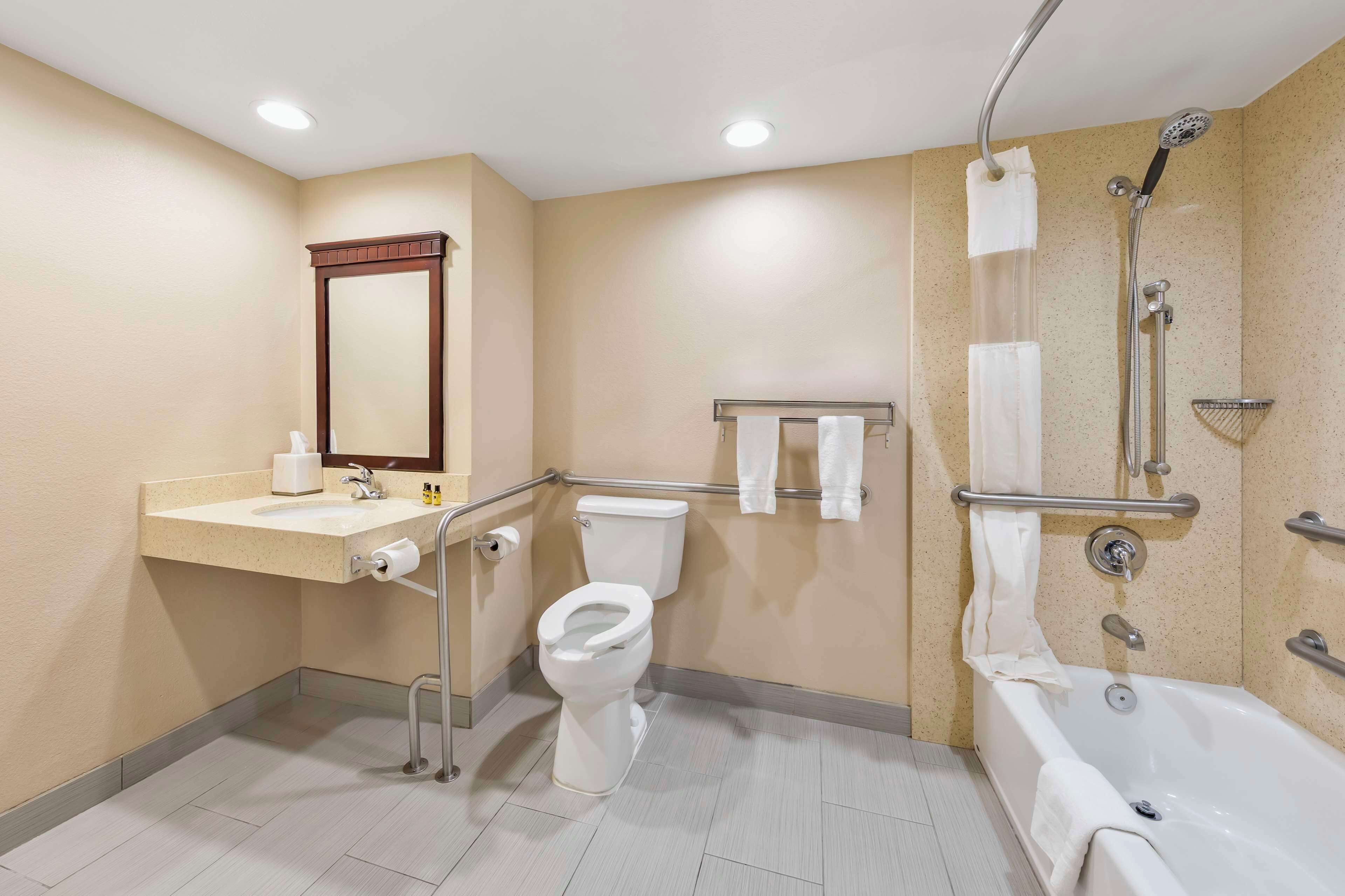 Un baño con inodoro, lavamanos, espejo, ducha y bañera.