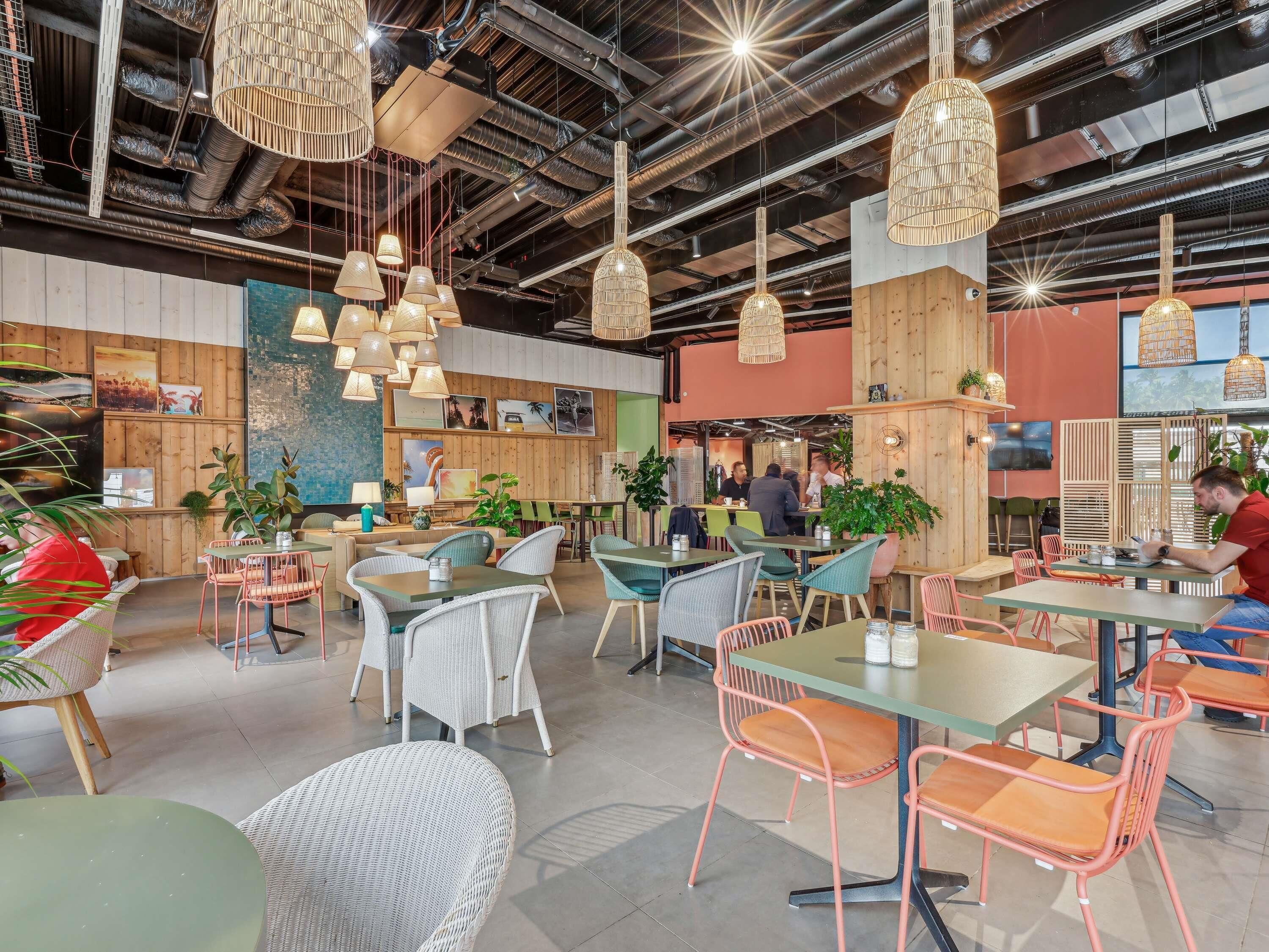 A spacious indoor area with multiple seating arrangements, including tables and chairs, and hanging pendant lights.