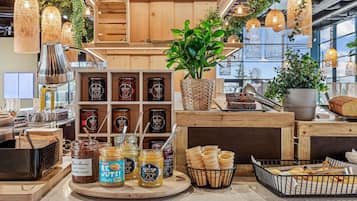 A bakery display with jars of honey, jars of peanut butter, and a variety of breads and pastries.