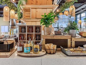 A bakery display with jars of honey, jars of peanut butter, and a variety of breads and pastries.