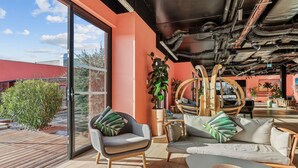 A modern interior with a large glass door leading to a patio, a sofa, a chair, and a table. - Mercure Paris Orly Airport (Paray-Vieille-Poste)