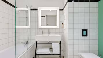 Uma casa de banho moderna com chuveiro separado por vidro, uma sanita e uma pia branca com espelho em cima.