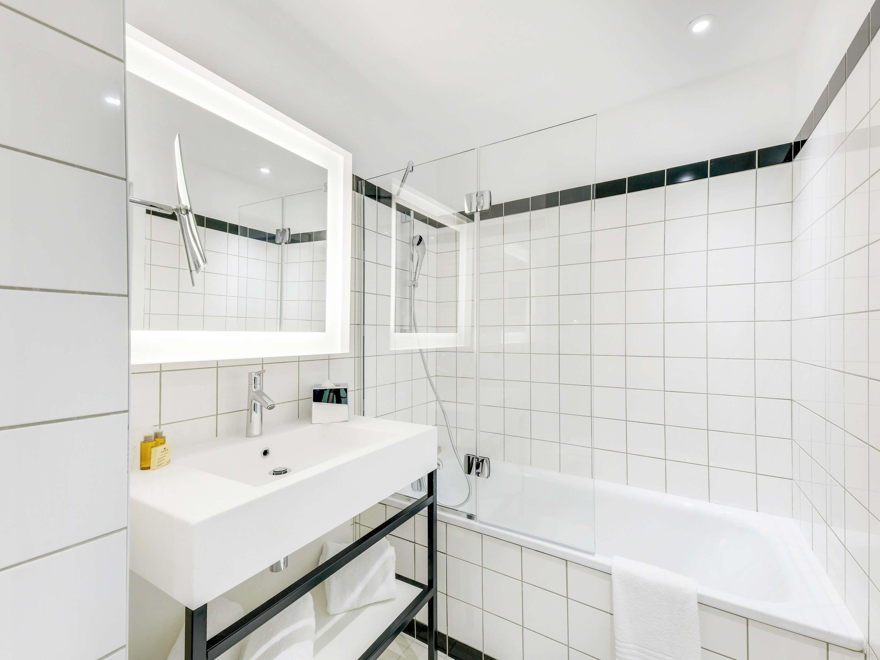 A modern bathroom with a white sink, mirror, and shower.