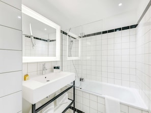 A modern bathroom with a white sink, mirror, and shower.