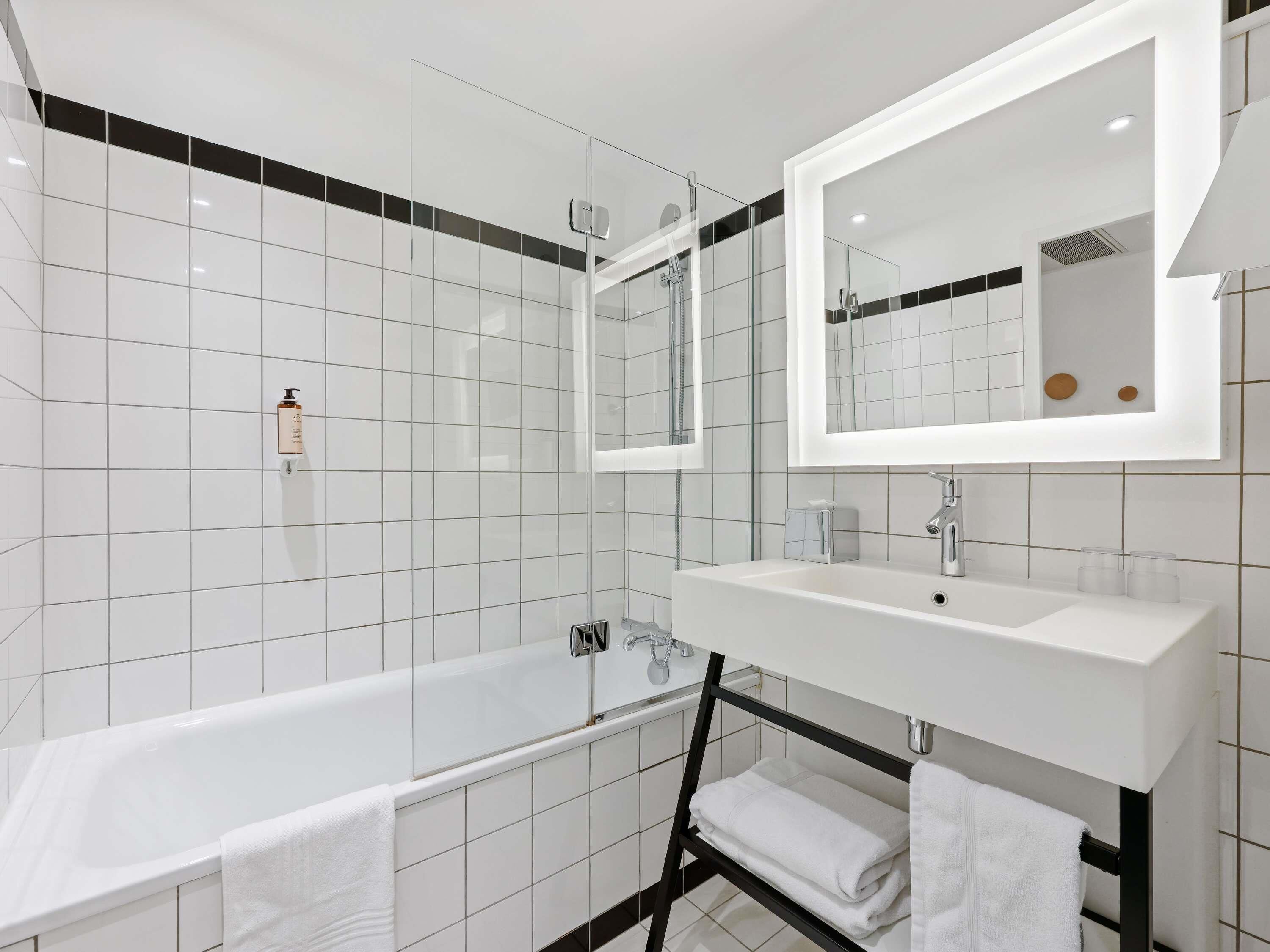 A modern bathroom with a bathtub, a sink, a mirror, and a towel rack.