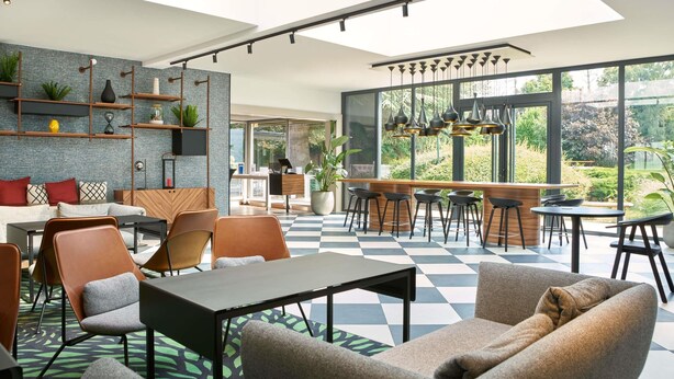 A modern interior with a checkered floor, a bar area, and a seating arrangement. - Novotel Massy Palaiseau (Palaiseau)