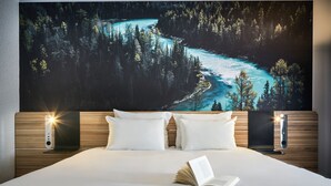 A bedroom with a large bed, two bedside tables, and a wall-mounted TV. - Novotel Massy Palaiseau (Palaiseau)