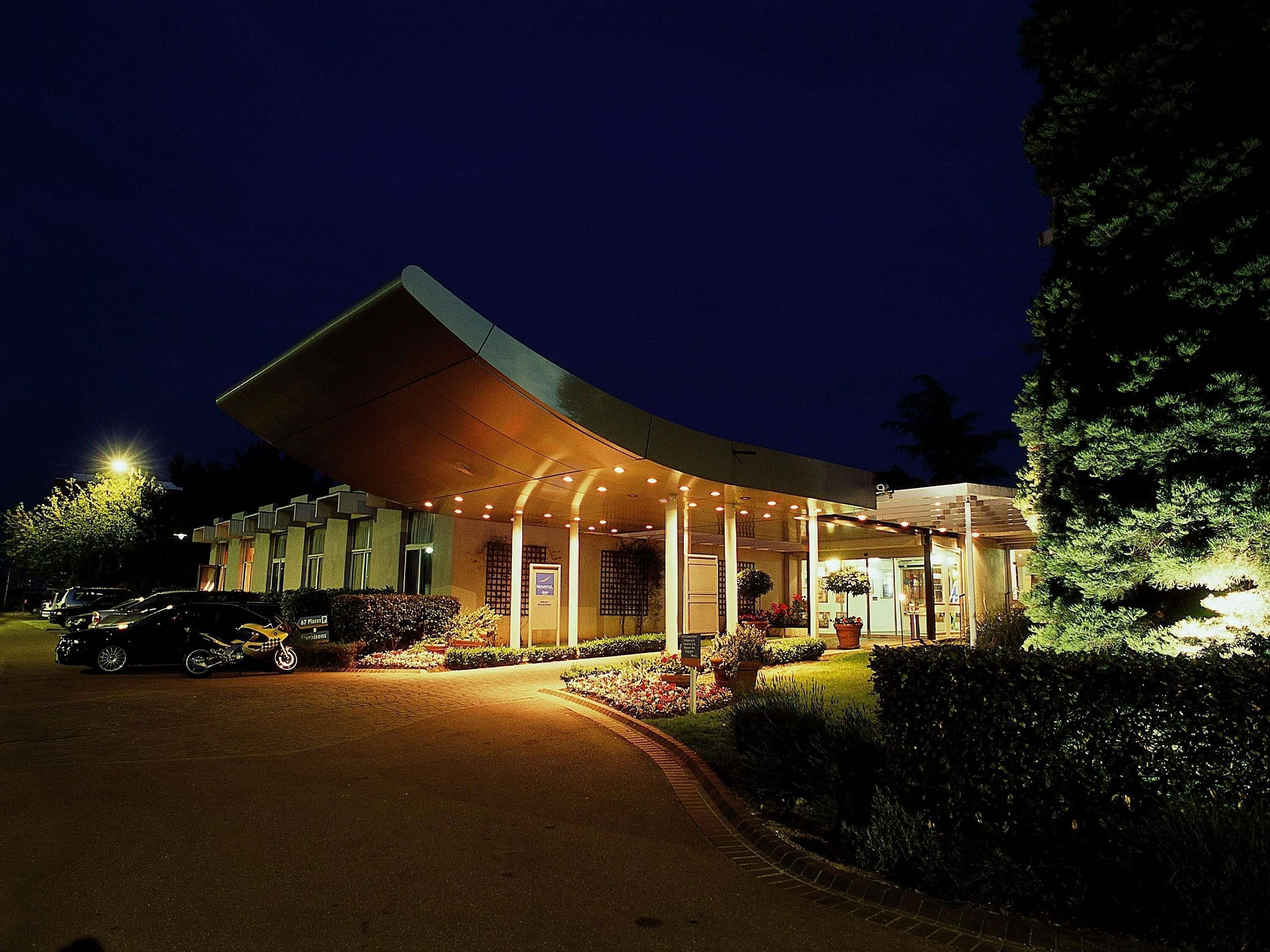 A hotel with a curved roof, a covered entrance, and a well-lit driveway.
