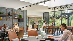 A modern cafe with a bar area, seating with tables and chairs, and large windows offering views of the outdoors. - Novotel Massy Palaiseau (Palaiseau)