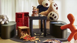 A room with a large teddy bear, a stack of books, and a wooden toy structure. - Novotel Massy Palaiseau (Palaiseau)