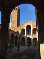 An architectural view of a courtyard with a tall tower and arched structures.