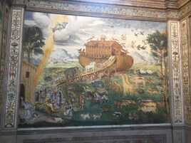 Een gedetailleerde muurschildering toont een bijbelse scène met een grote ark, verschillende dieren en figuren die met elkaar omgaan.