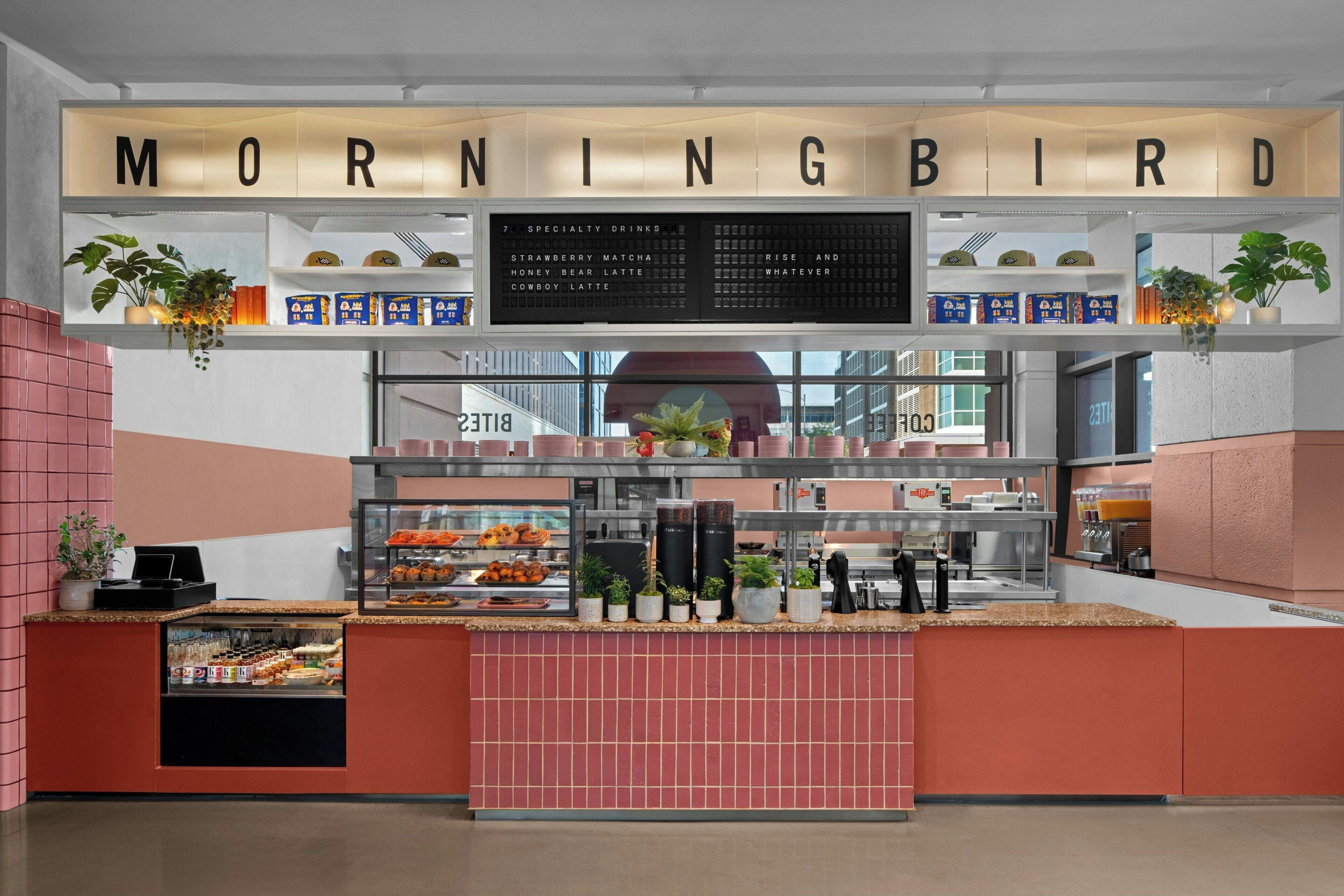 En frukostdisk med en meny som hänger ovanför, där det står ”MORNINGBIRD”, och ett urval av olika matvaror som visas upp.