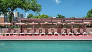 A poolside area with lounge chairs and umbrellas, a clear pool, and a cityscape in the background. - Renaissance Austin Downtown Hotel (Austin)