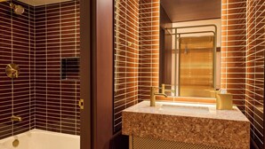 A bathroom with a bathtub, a sink with a marble countertop, and a shower area. - Renaissance Austin Downtown Hotel (Austin)