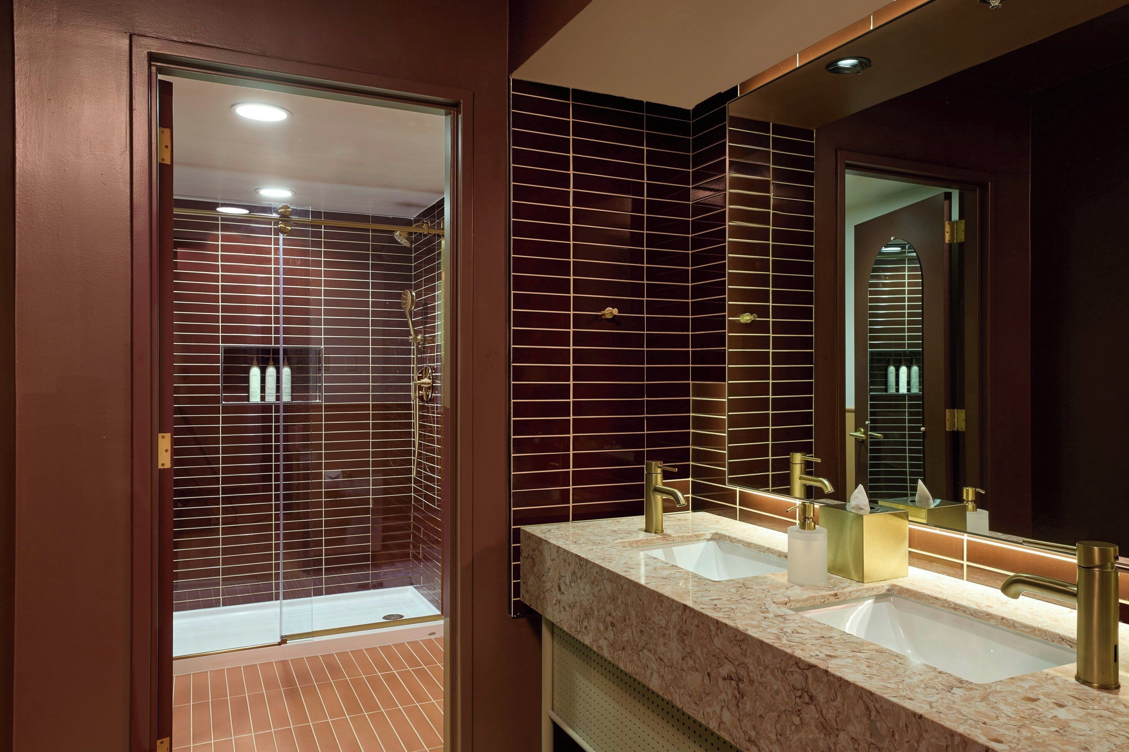 A modern bathroom with a dual sink vanity, a large mirror, and a shower area with a glass door.