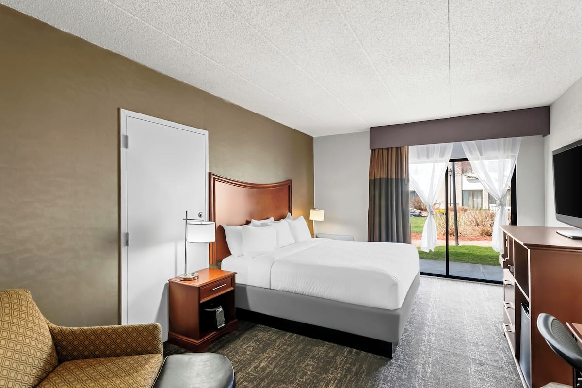 Une chambre d’hôtel avec un grand lit, un bureau, une chaise et un téléviseur.