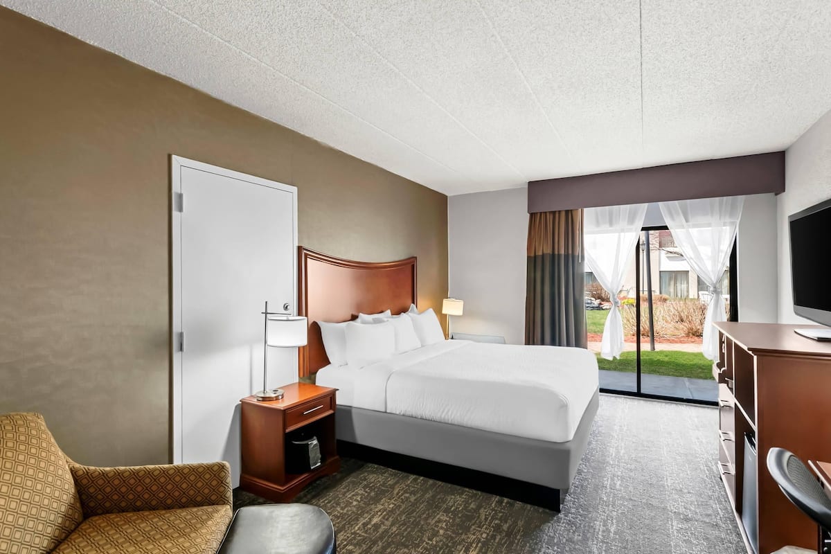 Une chambre d’hôtel équipée d’un lit, d’un bureau, d’une chaise, d’une télévision et offrant une vue sur l’extérieur.