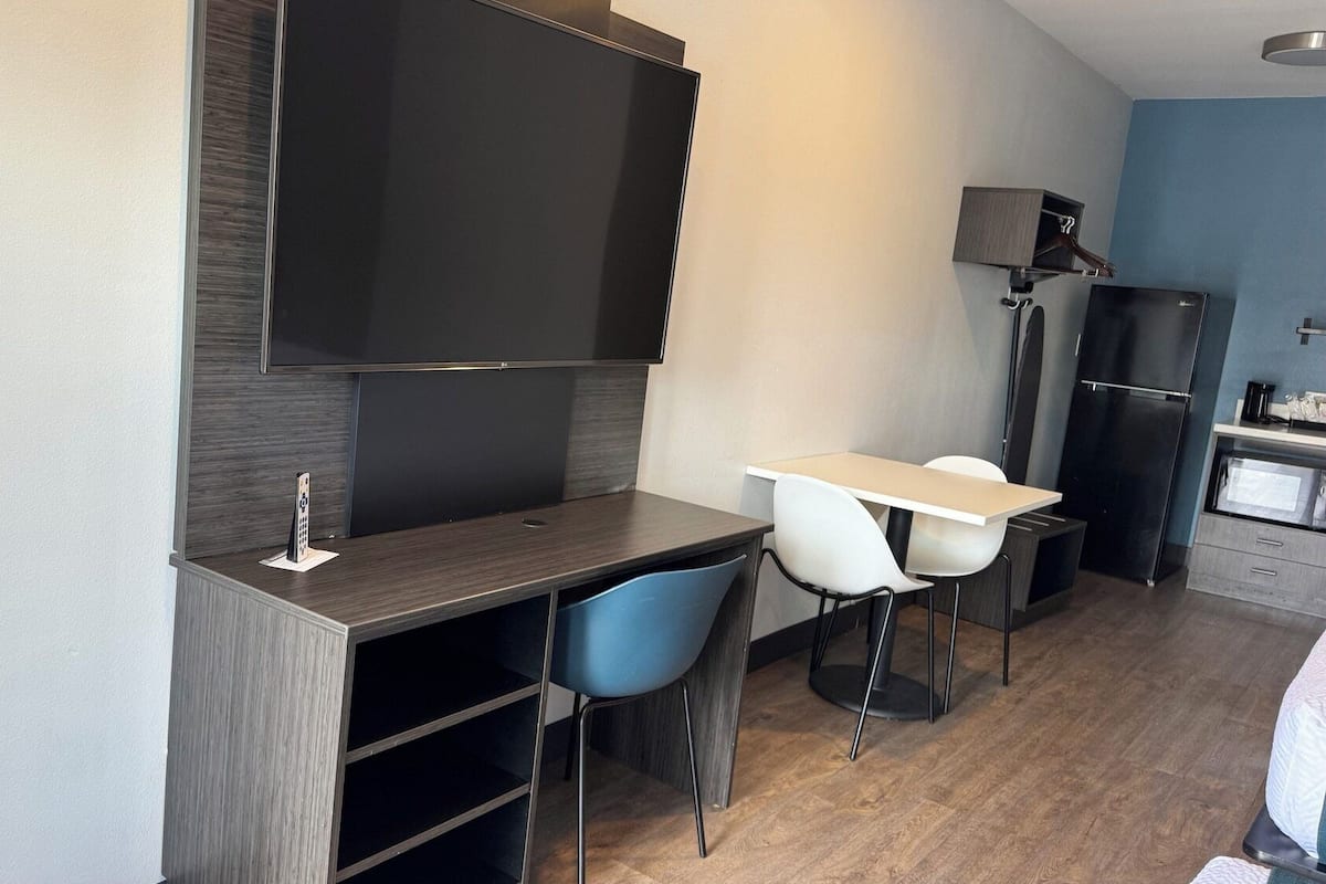 Una kitchenette compacta con un refrigerador negro, un microondas y una cafetera.